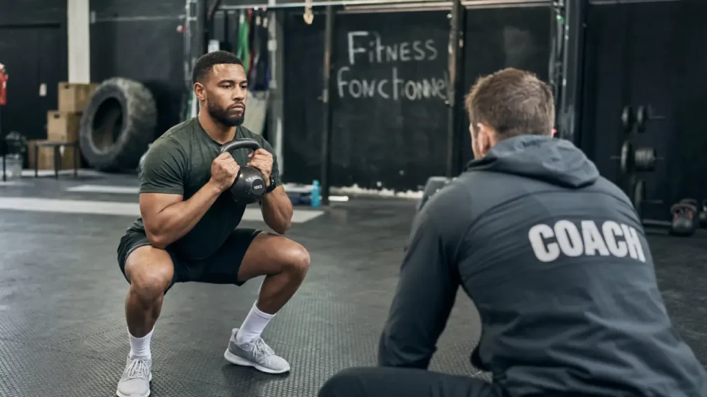 Fitness fonctionnel : squat contrôlé avec kettlebell en salle de sport